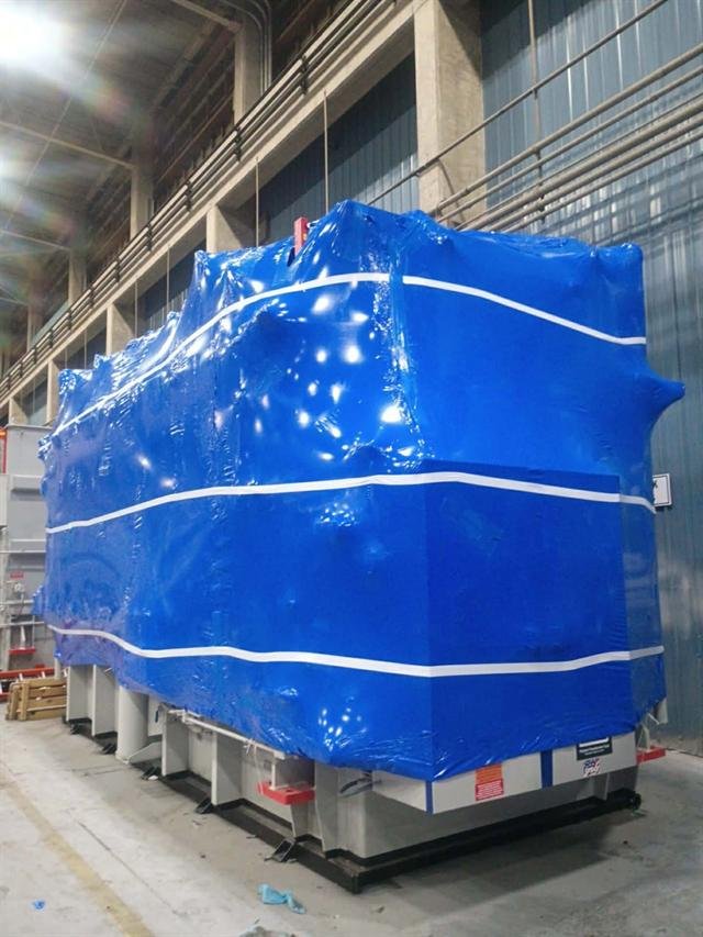 Row of large transformers protected in blue shrink wrap awaiting shipment